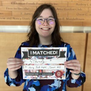 Lisette holds up a sign showing where she matched for residency