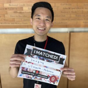 Yi-Hsuan stands in the lobby holding an I Matched sign