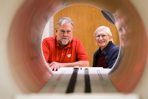 two people stand on the far end of a tube peering through it towards the camera