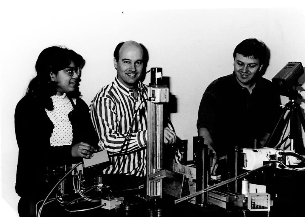 Wally Peppler and two students stand behind a piece of equipment