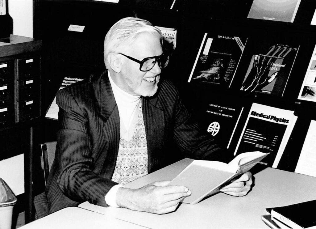 James Cameron sits at a desk reading a book