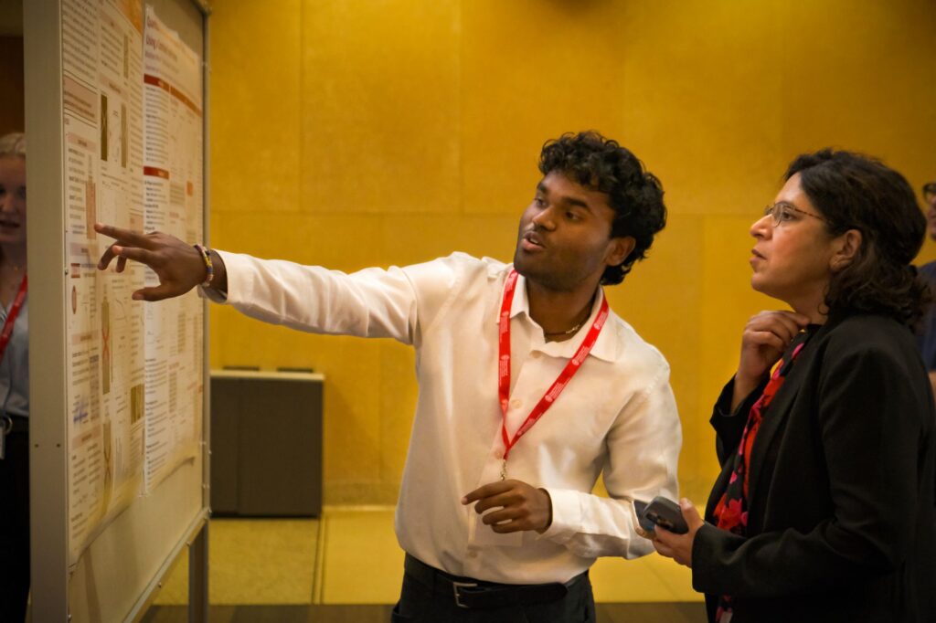 student stands with Dean Ahuja and shows his research
