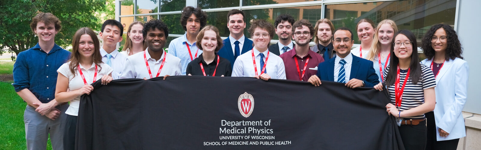 Assure students group photo outside holding a black cloth with logo